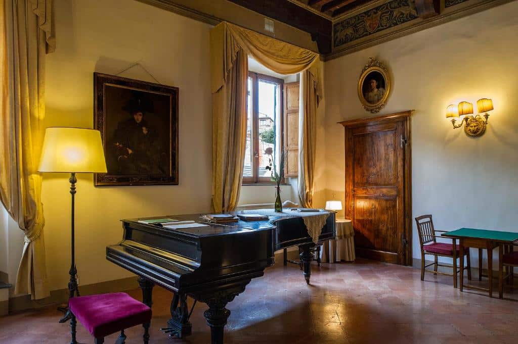 Piano de cauda preto numa sala clássica com decoração antiga e quadros na parede