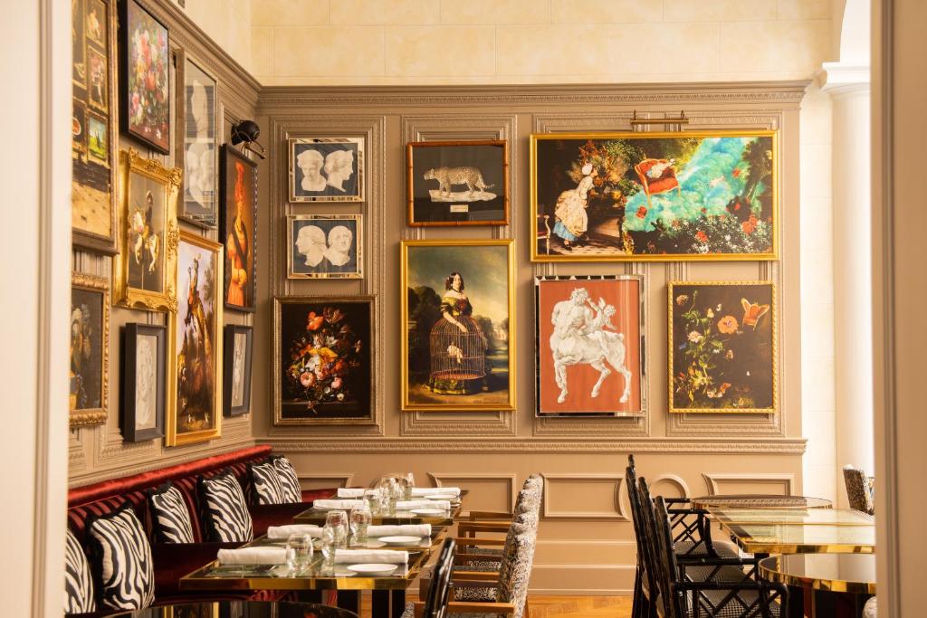sala do Maalot Roma, uma das opções de onde ficar em Roma, com mesas e cadeiras de madeira e obras de arte nas paredes