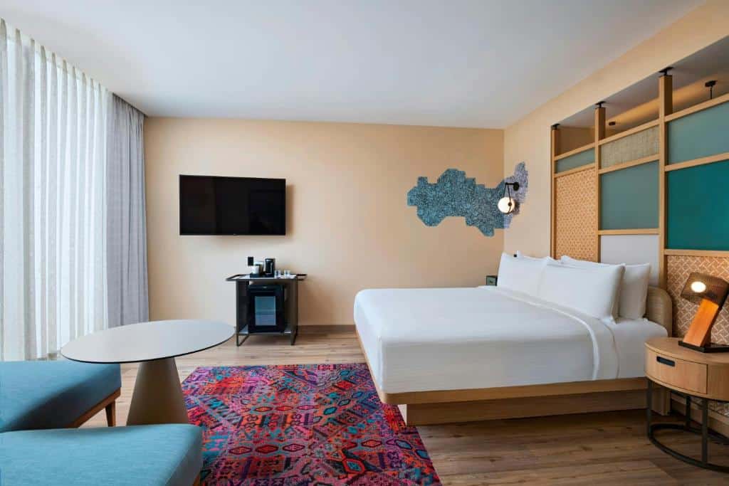 Quarto do Aloft by Marriott Playa del Carmen com cama de casal, mesa de centro e TV de ecrã plano.