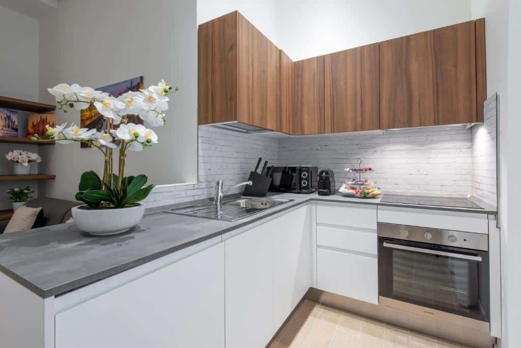 Cozinha do Milan Royal Suites – Centro com vários armários, forno, lava-loiça, micro-ondas e uma jarra de flores brancas sobre a bancada