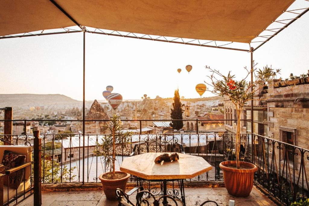 Terraço de cobertura do Sultan Cave Suites com vasos de plantas e vista sobre a cidade ao nascer do sol, com balões de ar quente no céu.
