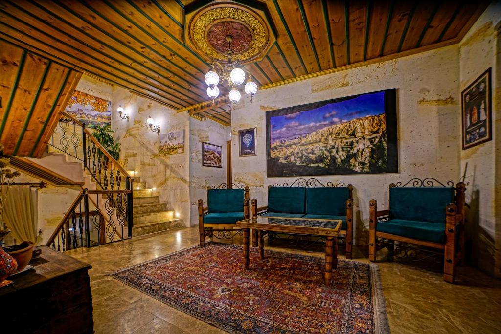 Lounge acolhedor do Milat Cave Hotel, um dos hotéis da Capadócia, com tecto de madeira, sofás verdes, tapete estampado, arte na parede e uma escada com corrimão de ferro.