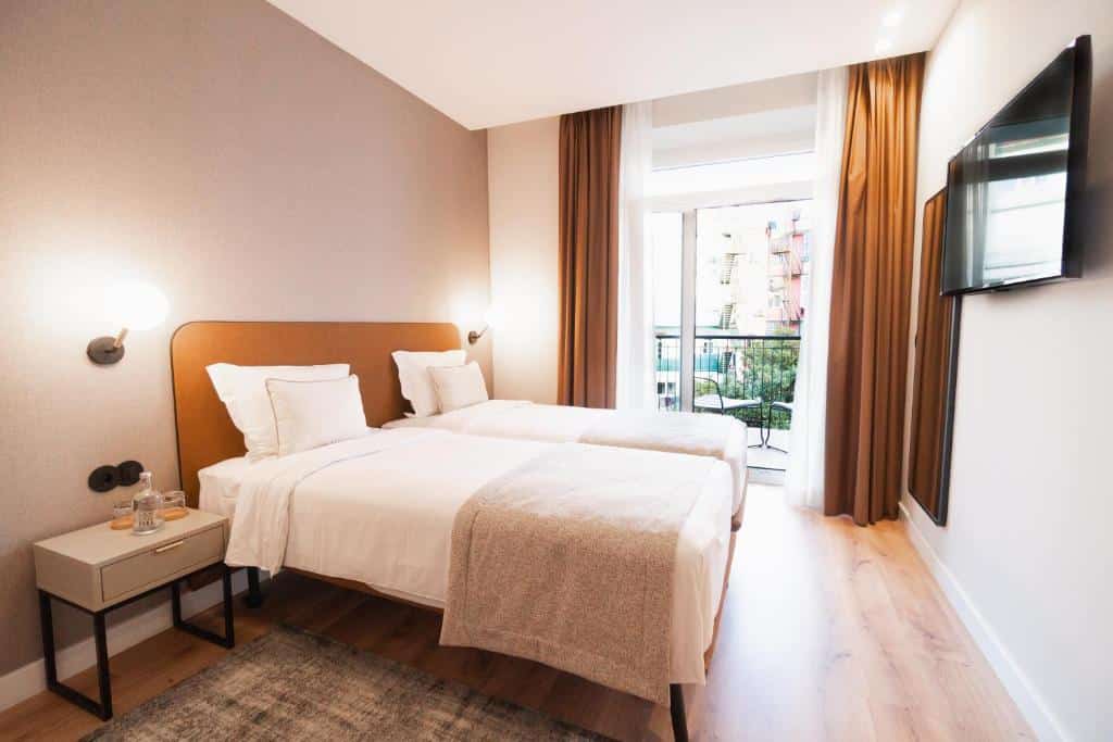 Quarto do LX SoHo Boutique Hotel com uma varanda virada para a avenida, duas camas individuais e, na parede em frente, um espelho de corpo inteiro e uma televisão.
