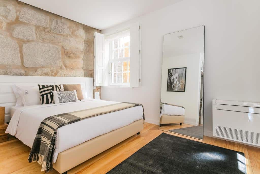 Quarto do Porto River, com cama de casal à esquerda e um espelho à direita.