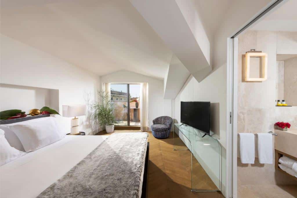 quarto do Hotel Palazzo Manfredi, um dos hotéis de luxo em Roma, com cama enorme, televisão em frente, poltrona e varanda com vista da cidade