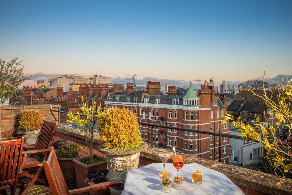 Terraço do San Domenico House com vista para a cidade, mesas e cadeiras de madeira e alguns vasos de plantas.
