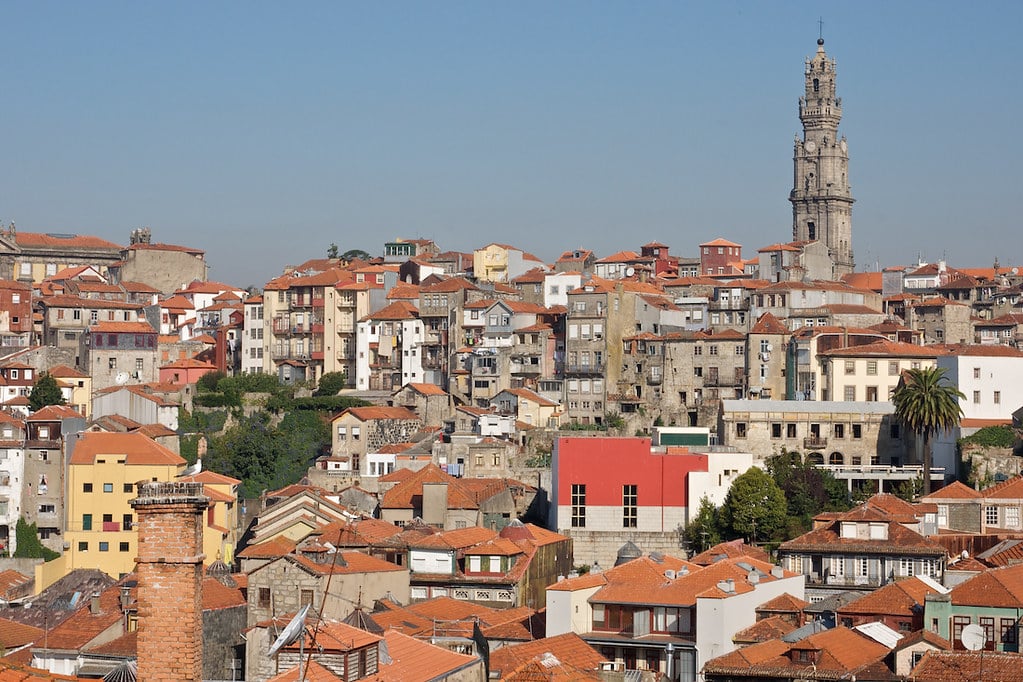Vista do Porto durante o dia, com várias casas e a Torre dos Clérigos ao fundo, à direita.