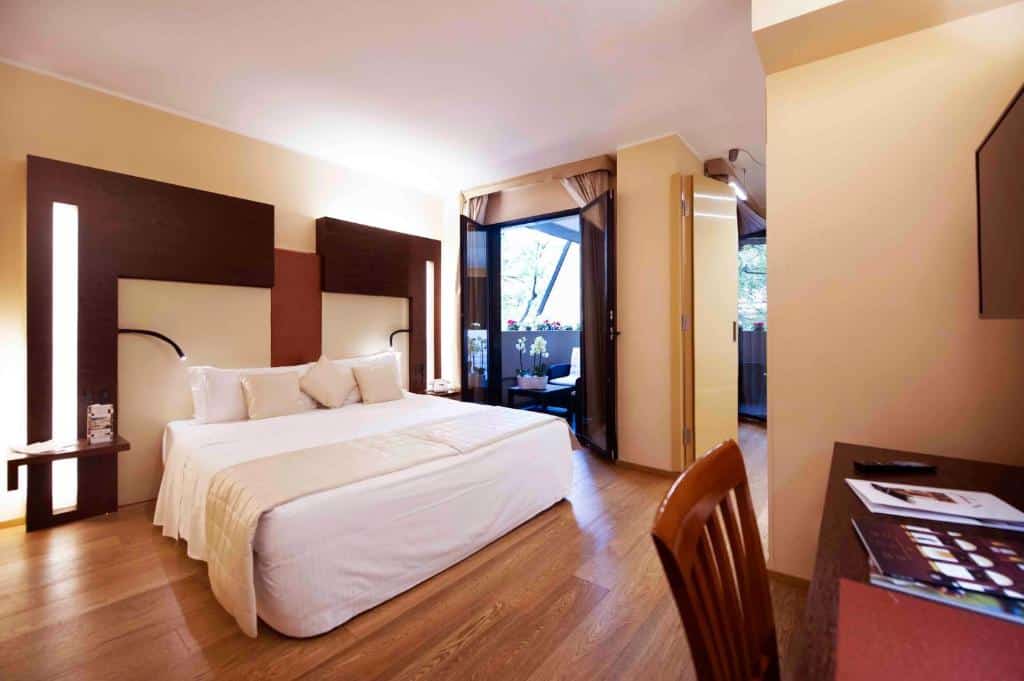 Quarto com cama de casal, secretária e cadeira em madeira e porta para a varanda no Art Hotel Navigli