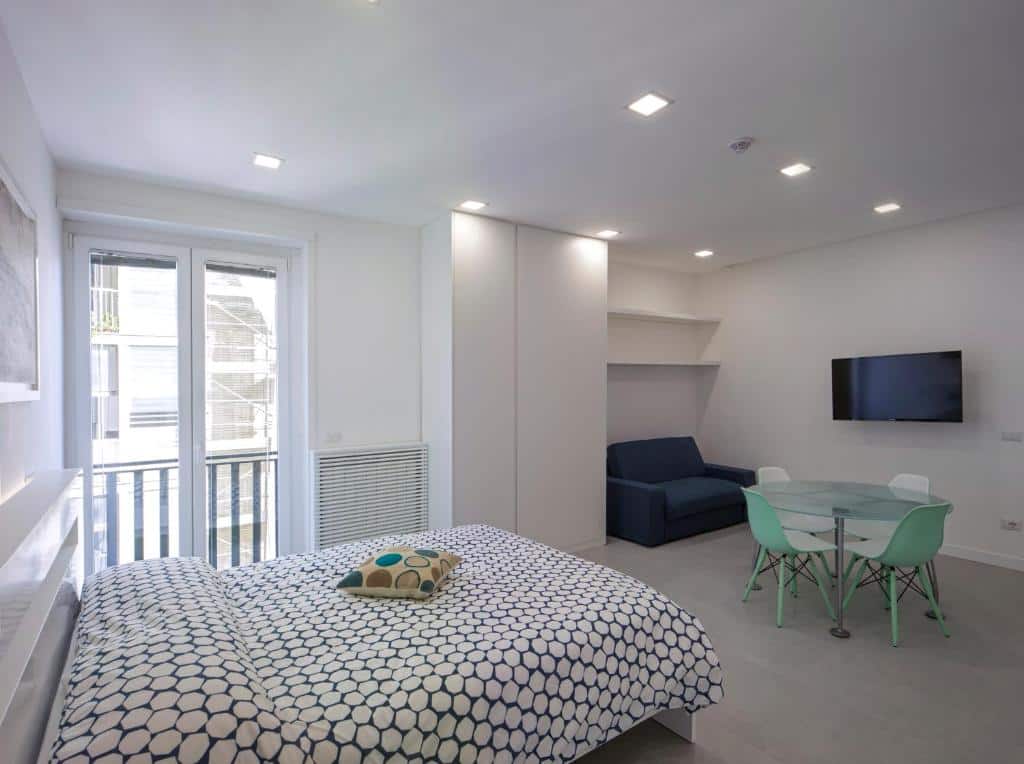 Sala de estar moderna do Relais Castel Nuovo com sofá azul-marinho, mesa de jantar de vidro e cadeiras verdes.