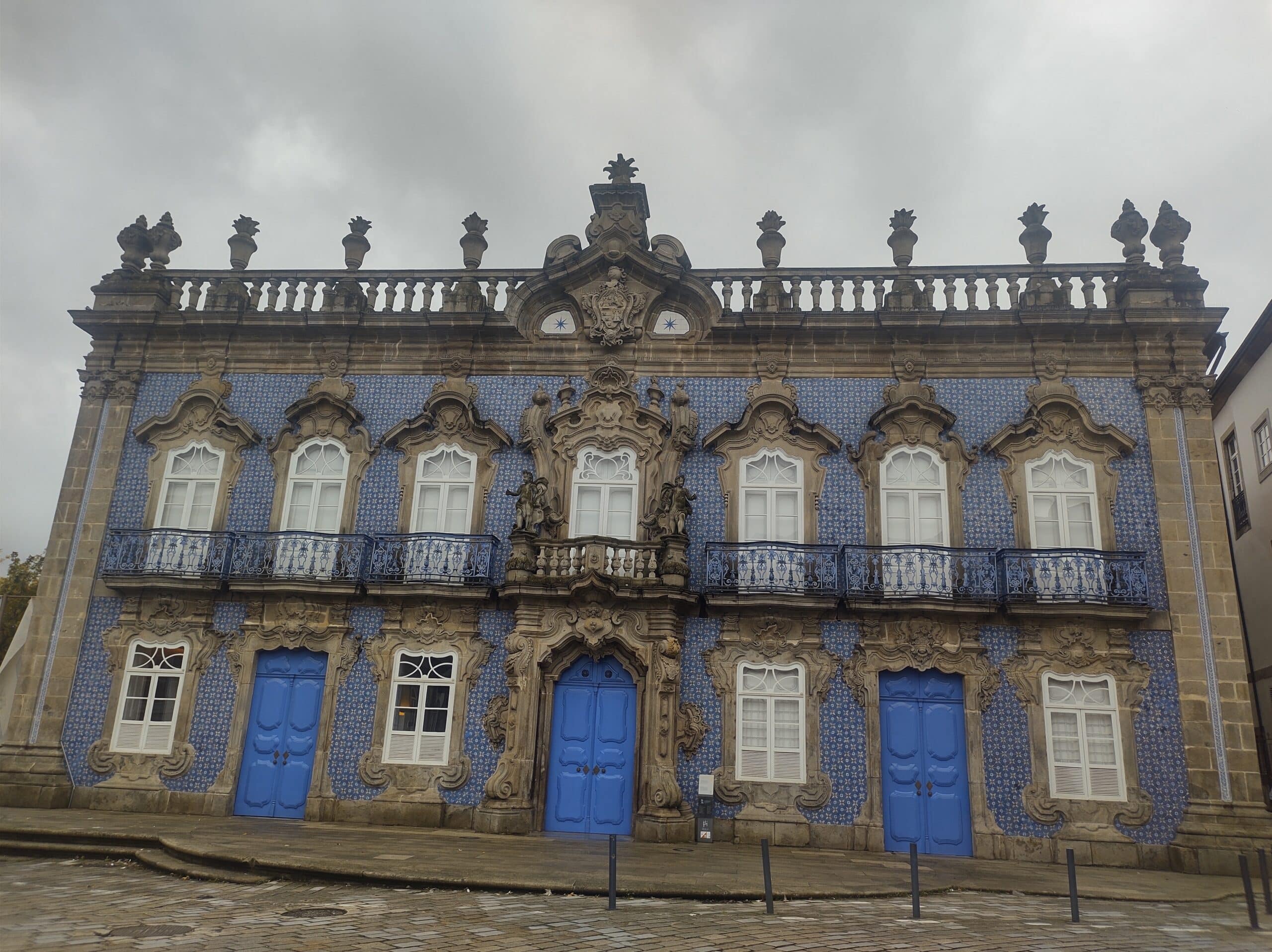 Vista diurna do Palácio do Raio, em Braga, com azulejos na fachada e portas azuis.