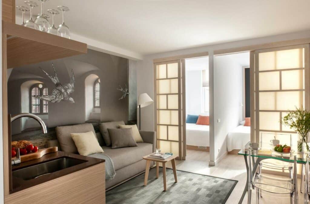Apartamento do Eric Vökel Boutique Apartments – Copenhagen Suites. Tem um sofá, uma bancada de cozinha, mesa de refeições e dois quartos ao fundo.
