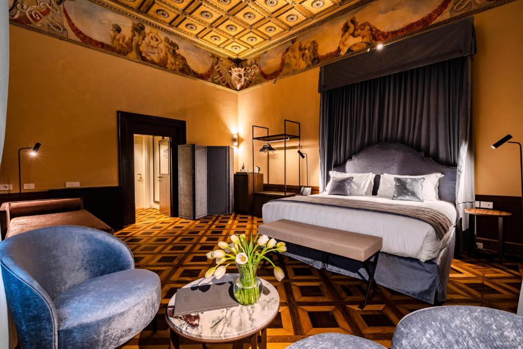 Quarto de hotel luxuoso com detalhes ornamentados no teto, cama de casal com dossel e mobiliário sofisticado em tons escuros