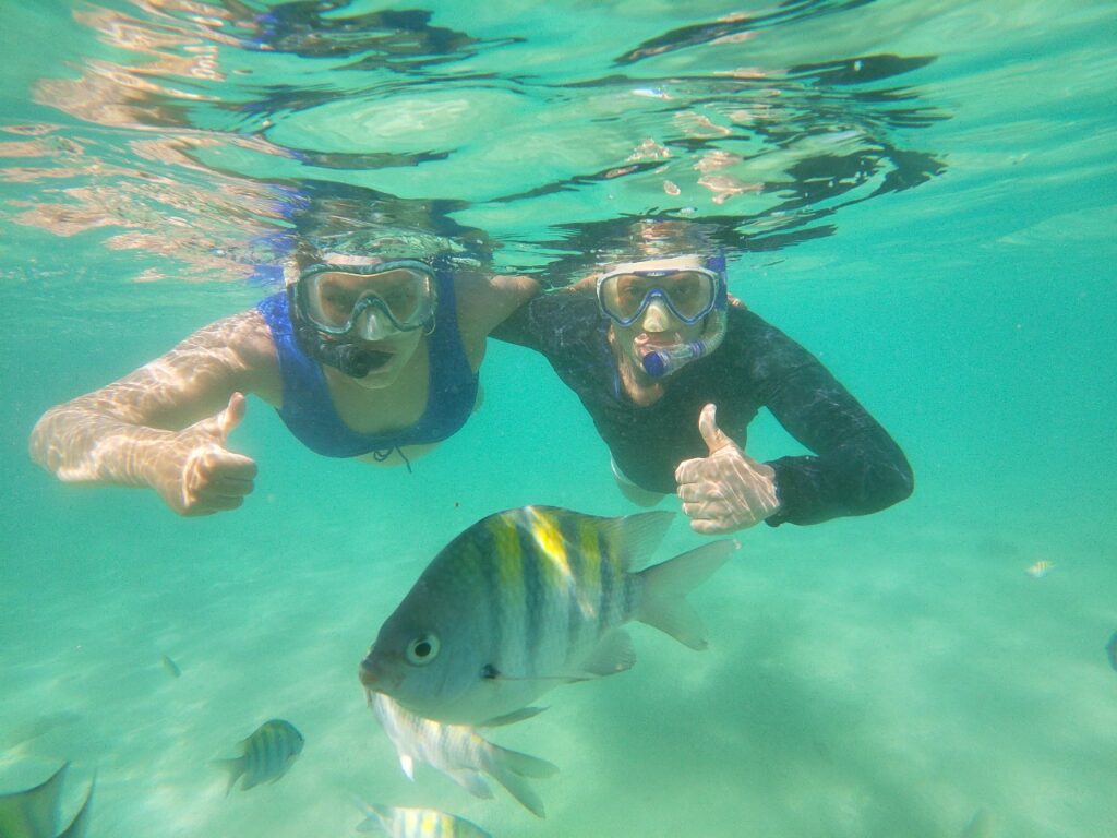 Casal a mergulhar perto de um peixe tropical em águas azul-turquesa cristalinas em Maragogi