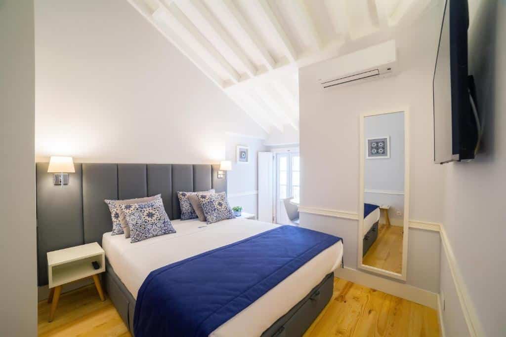 Quarto do Villa Baixa - Lisbon Luxury Apartments com uma cama de casal com almofadas; do lado direito há uma pequena varanda, um espelho e ar condicionado de teto, e em frente à cama uma televisão