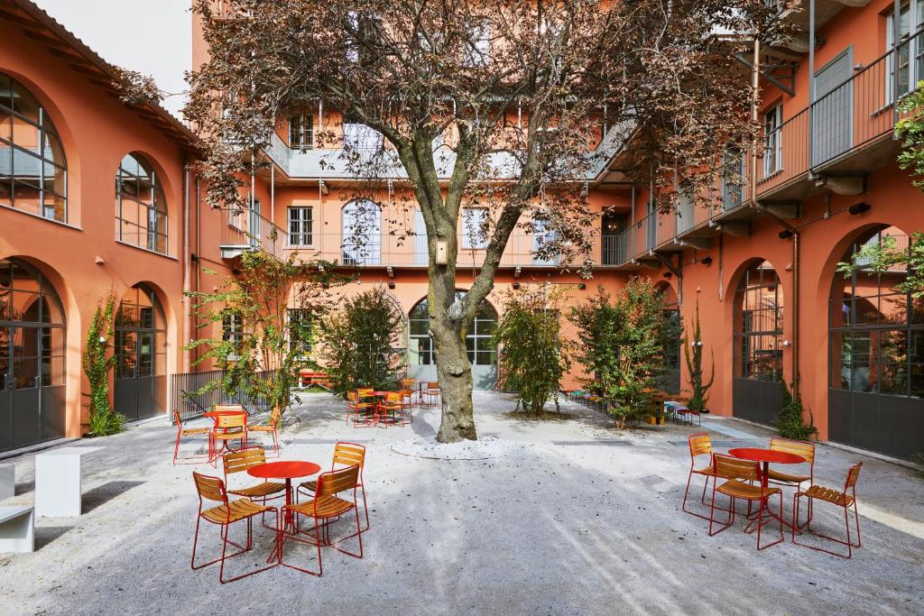 Terraço do Combo Milano com uma árvore ao centro e outras mais pequenas, mesinhas e cadeiras pelo espaço