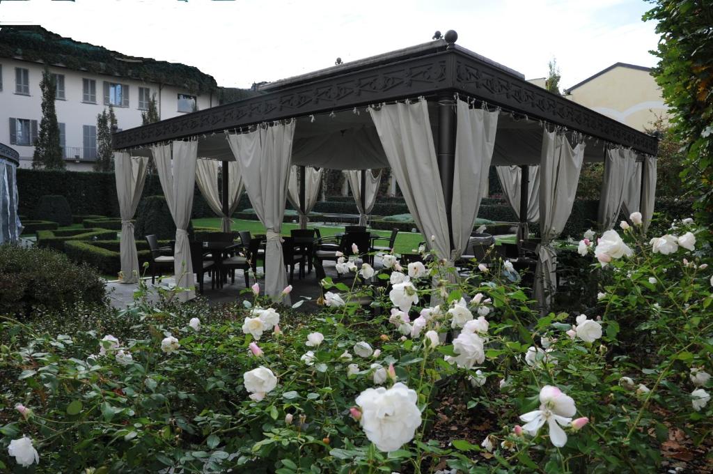 Jardim com flores brancas, uma estrutura tipo tenda em madeira e tecido e cadeiras no Grand Visconti Palace