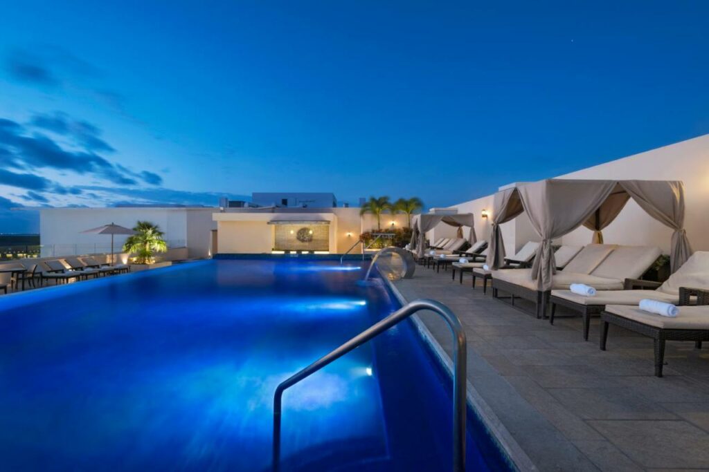 Piscina no Four Points by Sheraton Cancun Centro com bangalós e espreguiçadeiras no deck