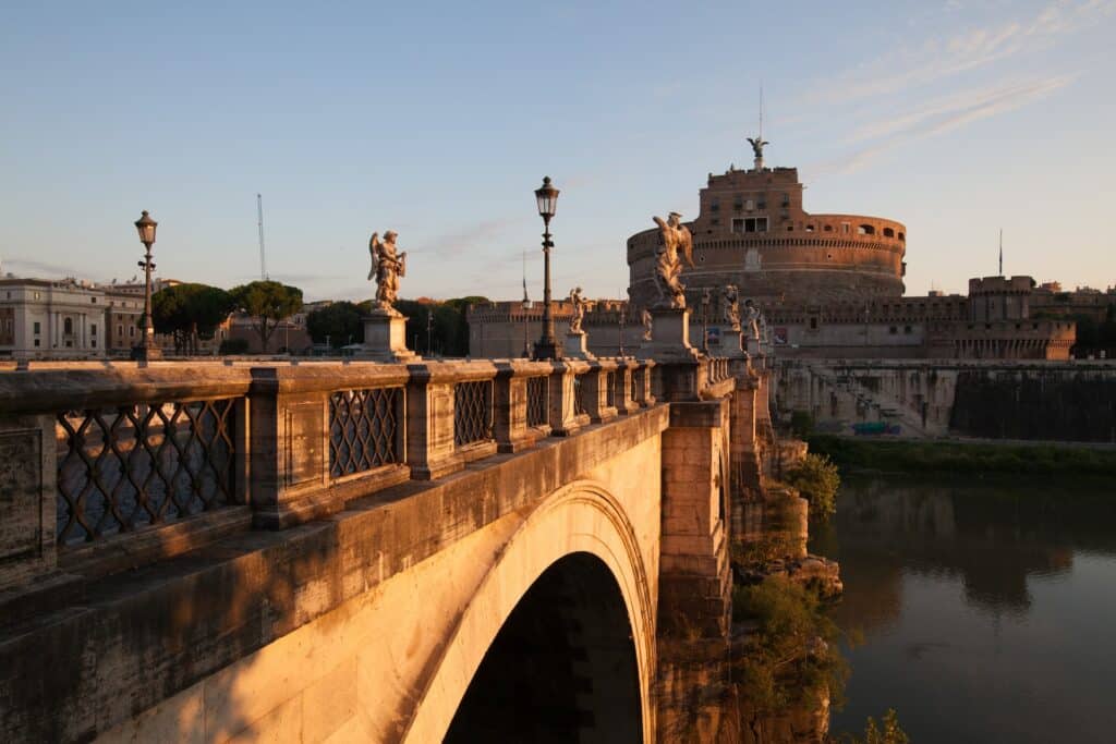 vista da ponte de pedra com várias esculturas de anjos que dá acesso à fortaleza do Castelo de Santo Ângelo, com um grande anjo esculpido por cima, em Roma