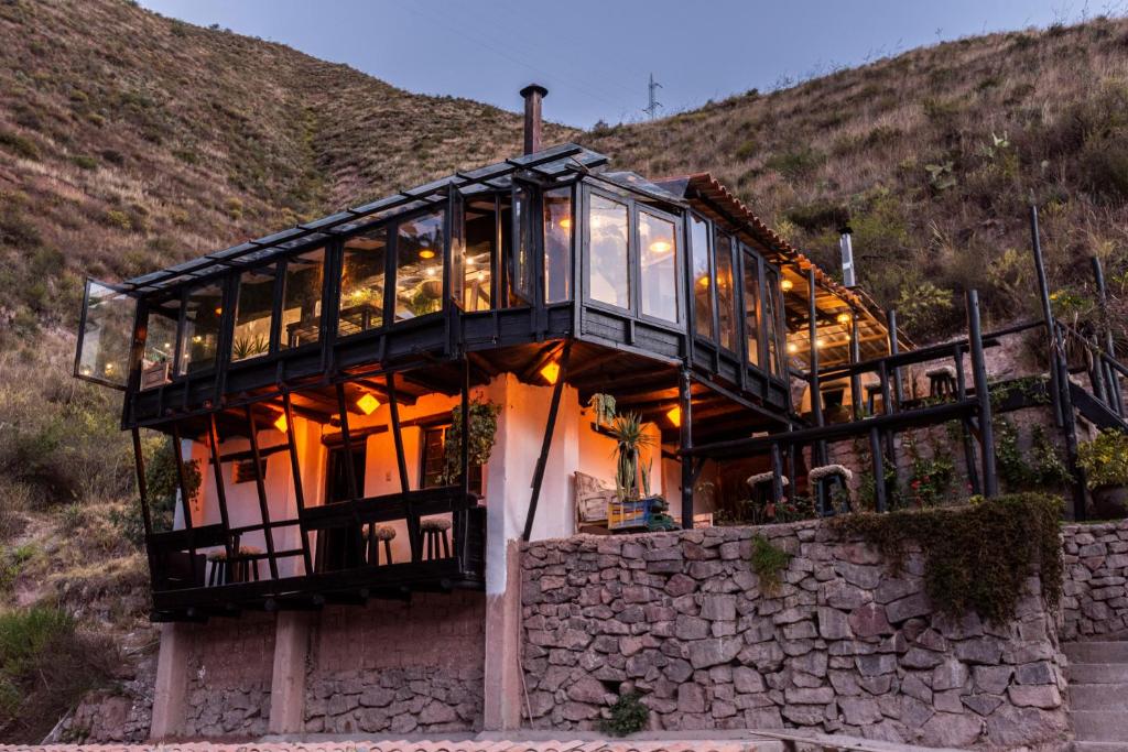 Fachada do Wolf Totem Guesthouse, um edifício de dois pisos sobre um muro de pedra, com o piso superior revestido a vidro