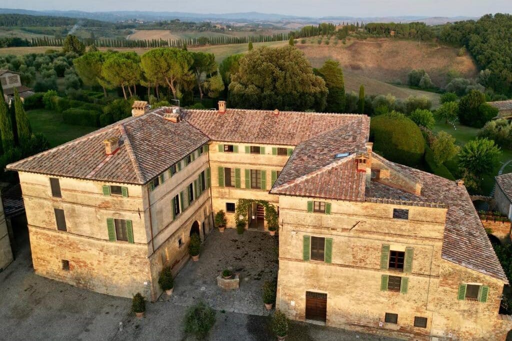 Casa de campo italiana com telhado de telha e janelas verdes numa paisagem rural toscana