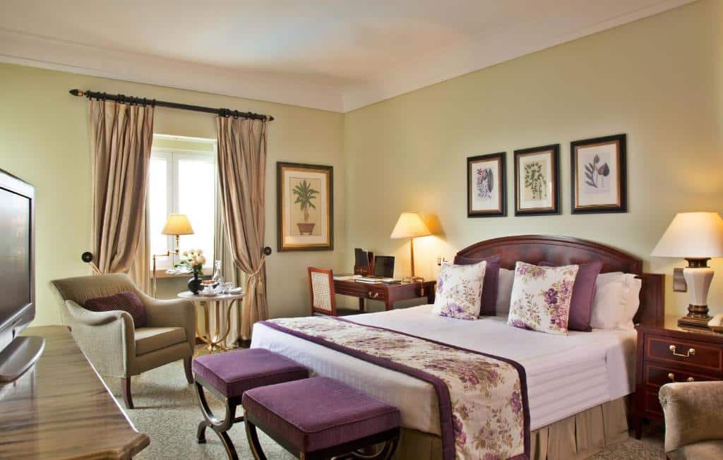 Quarto do Palácio Estoril Hotel com cama de casal, secretária com cadeira e móvel com televisão