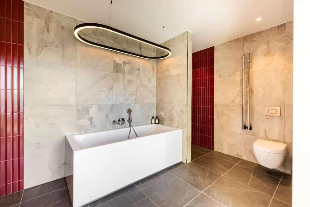 Casa de banho do hotel NH Collection Copenhagen com banheira, candeeiro por cima e sanita.