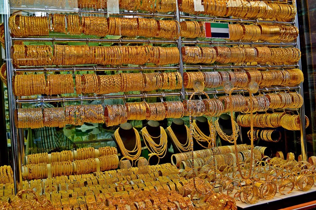Uma montra do Gold Souk repleta de filas de pulseiras e colares de ouro, dispostos de forma ordenada em suportes.