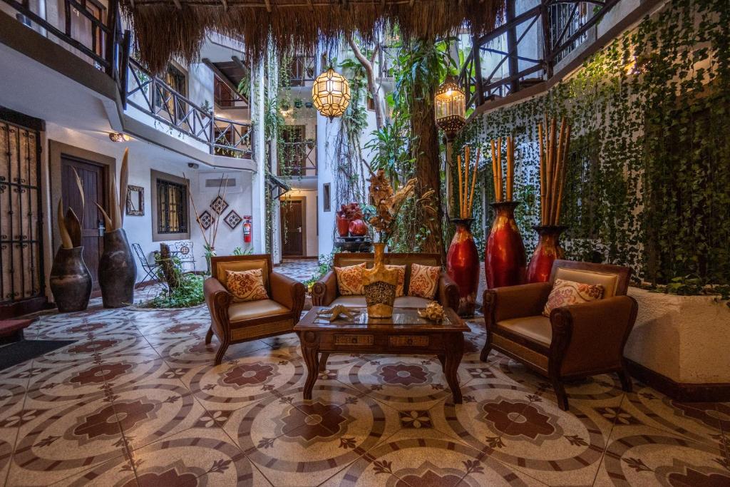 Pátio interior do Posada Mariposa Boutique Hotel com decoração colonial, móveis de madeira, pavimento em cerâmica floral e parede verde com plantas.