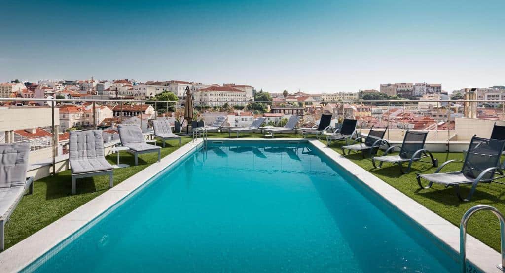 Piscina do NH Collection Lisboa Liberdade na cobertura, com vista sobre a cidade, espreguiçadeiras e cadeiras no deck.