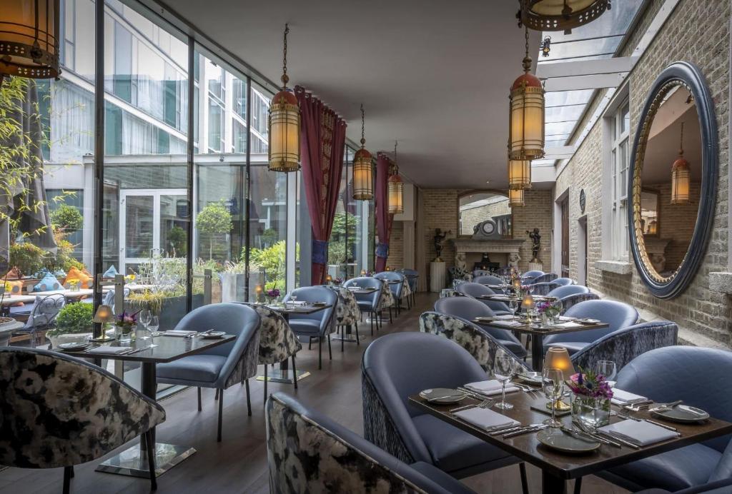 Restaurante elegante no The Trinity City Hotel com ambiente acolhedor e decoração cuidada, com mesas, cadeiras estofadas, lustres vintage e paredes de tijolo à vista.