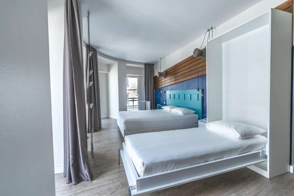 Quarto do Ibis Styles Lisboa Centro Liberdade NE com uma cama de casal, uma de solteiro, duas varandas e uma televisão