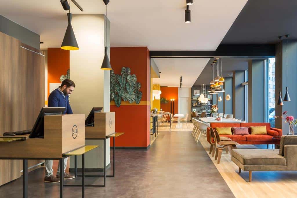 Receção do B&B Hotel Milano Central Station, com dois balcões e decoração colorida em tons de vermelho, laranja e azul