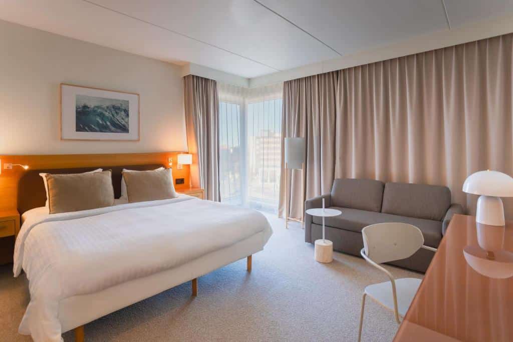Quarto do Courtyard by Marriott Stockholm Kungsholmen com mesa, cadeira, cama de casal e sofá.