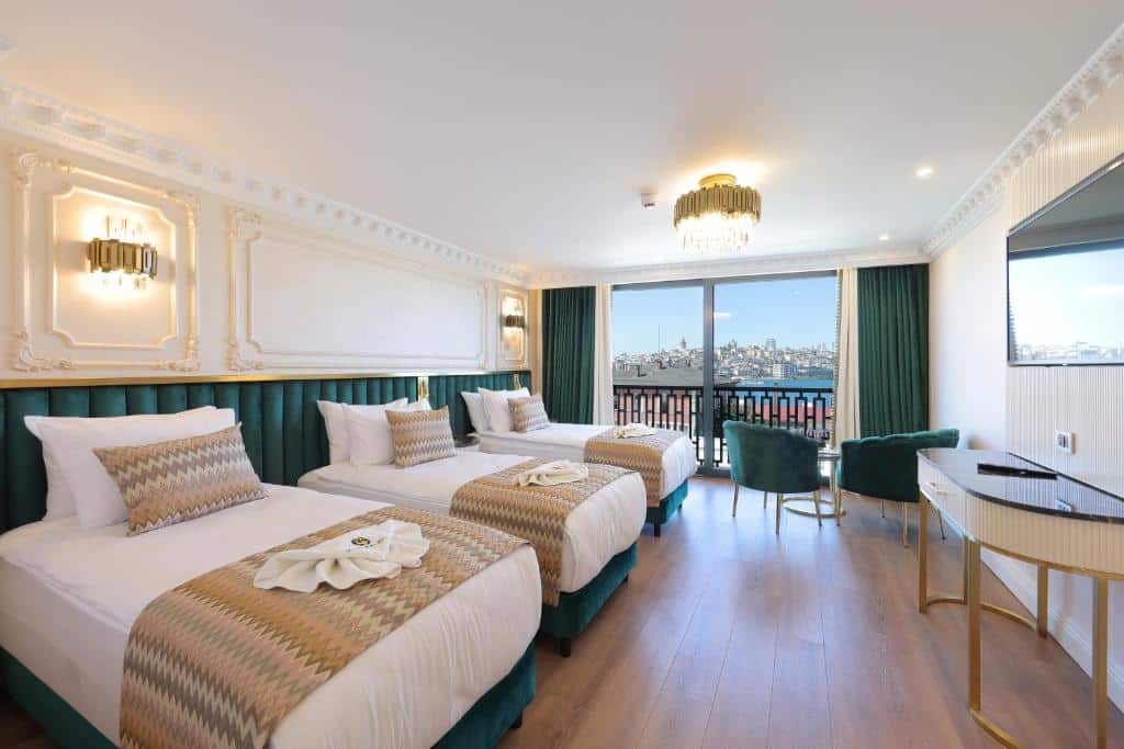 Quarto do Golden Horn Bosphorus Hotel com três camas de solteiro, varanda, vista para a cidade, TV, secretária e detalhes em verde na decoração.