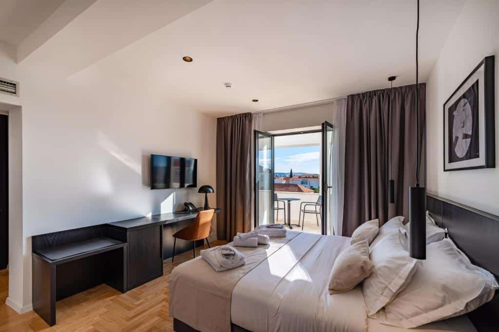 Quarto de hotel moderno com cama de casal, secretária e vista para cidade histórica, no Miramare Hotel, em Kolovare