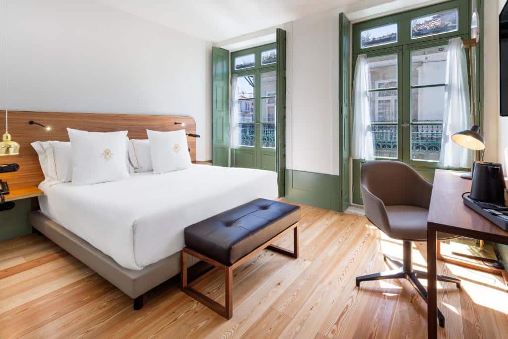 Quarto do One Shot Aliados Goldsmith 12 com cama de casal e, em frente, uma secretária de madeira com cadeira.