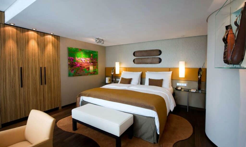 Quarto do Hotel Kö59 Düsseldorf com cama de casal ao centro e poltrona ao fundo da cama. Representa hotéis em Dusseldorf.