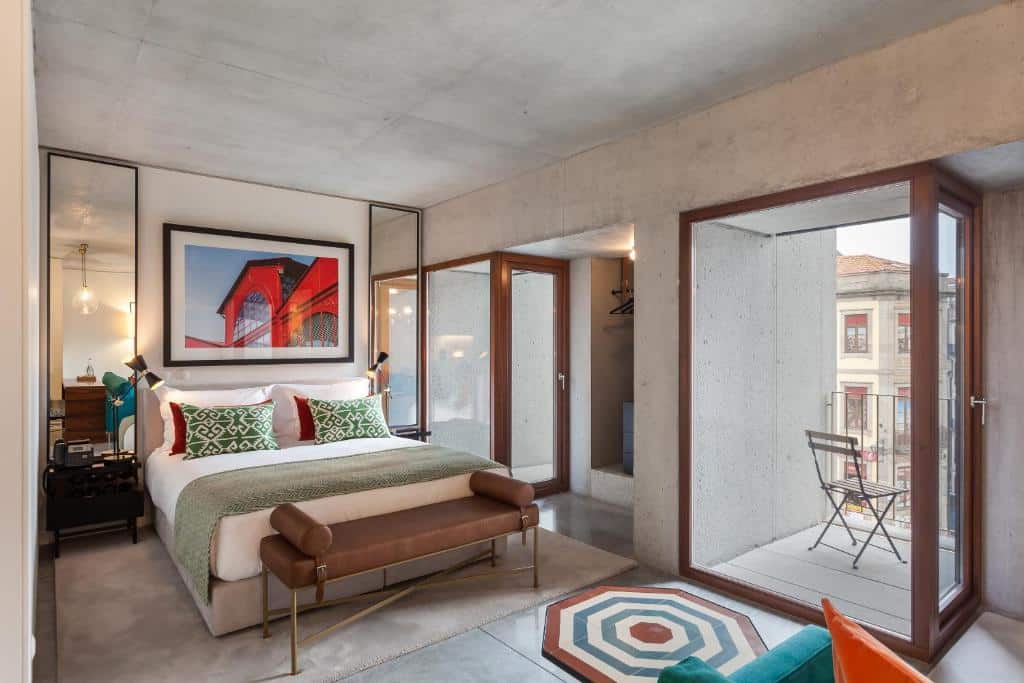 Quarto do S.Bento Residences, com cama de casal à esquerda, duas mesas de cabeceira com candeeiro e um sofá ao fundo.