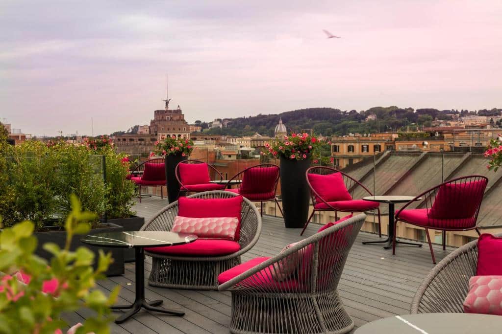 terraço do Orazio Palace Hotel, uma das opções de onde ficar em Roma, com mesas e poltronas de vime com almofadas vermelhas e vista para a cidade