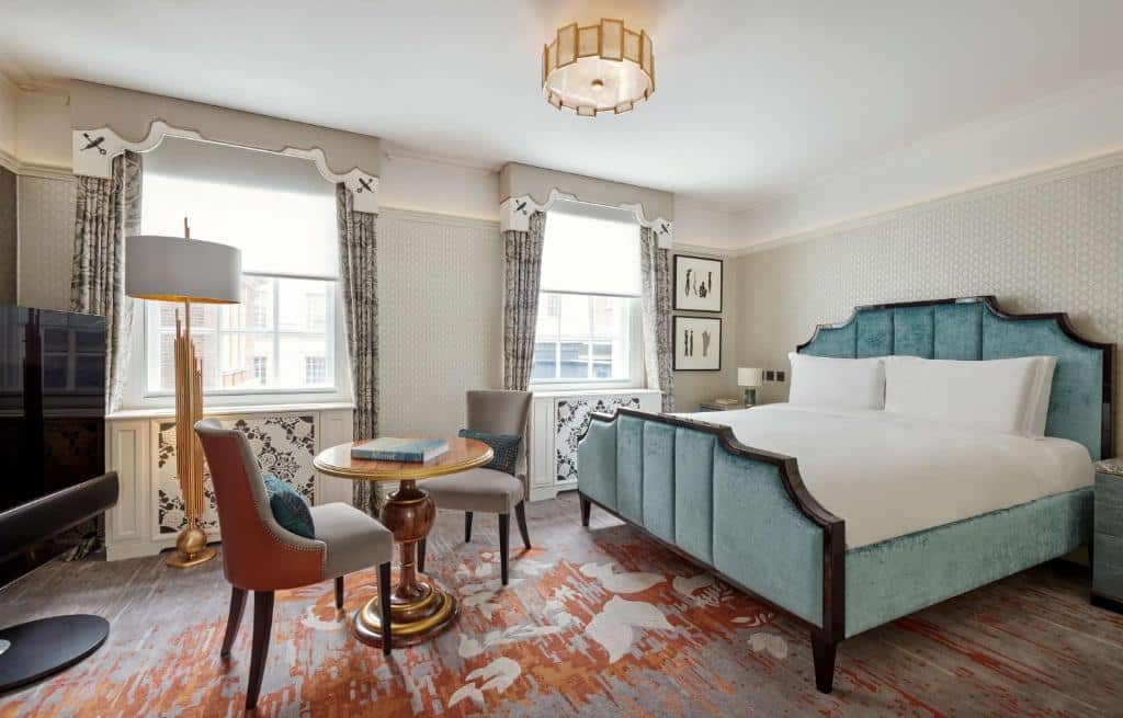 Quarto do Great Scotland Yard Hotel, part of Hyatt, com cama de casal, duas janelas com cortinas, um tapete amplo, uma mesa redonda com duas cadeiras estofadas e uma televisão.