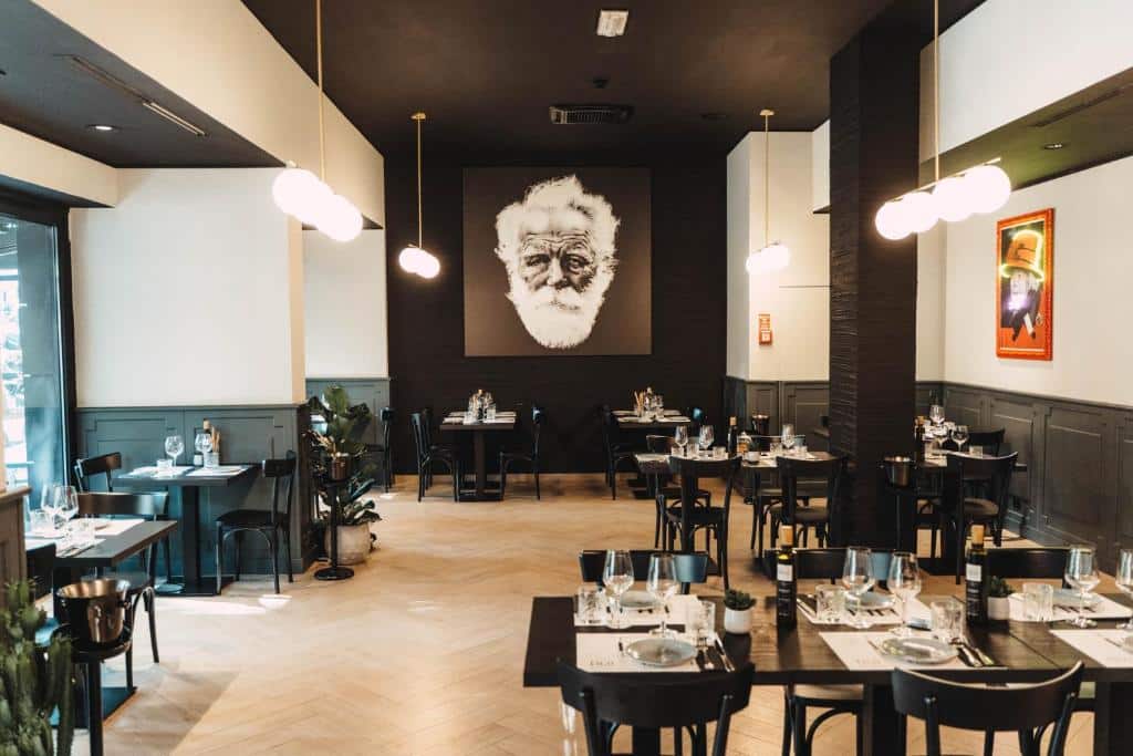 salão do Noba Hotel e Residenze com decoração moderna, mesa e cadeiras pretas com pormenores brancos e candeeiros em forma de bola por cima