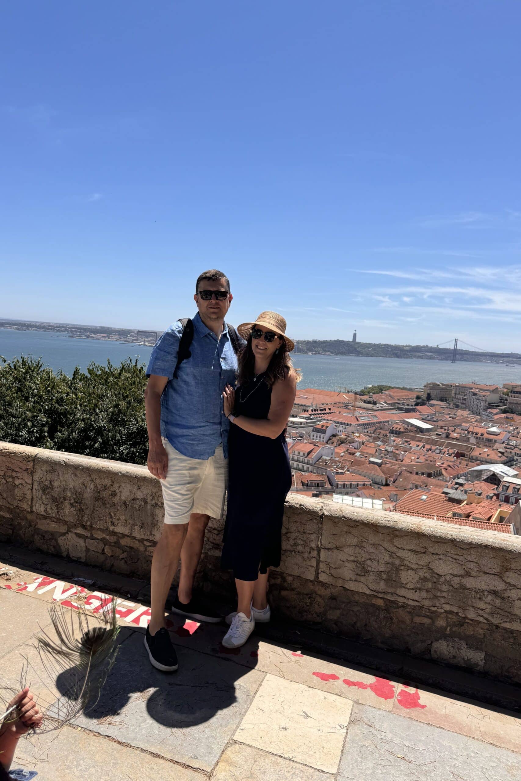 Casal a sorrir num miradouro com vista para a Ponte 25 de Abril, em Lisboa, Portugal