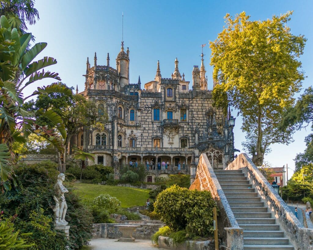 A Quinta da Regaleira, em Sintra, um palácio de época com pequenas torres, escadaria de pedra e jardim