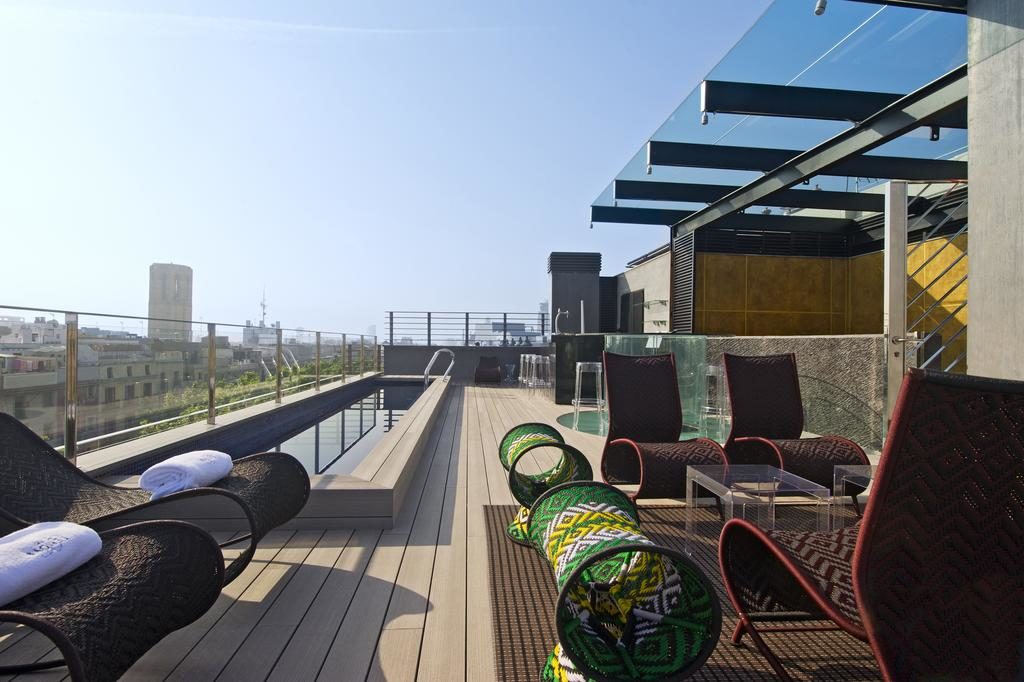 Cobertura do Hotel Bagués, com piscina protegida por uma balaustrada de vidro com vista para a cidade e várias espreguiçadeiras com mesinhas.