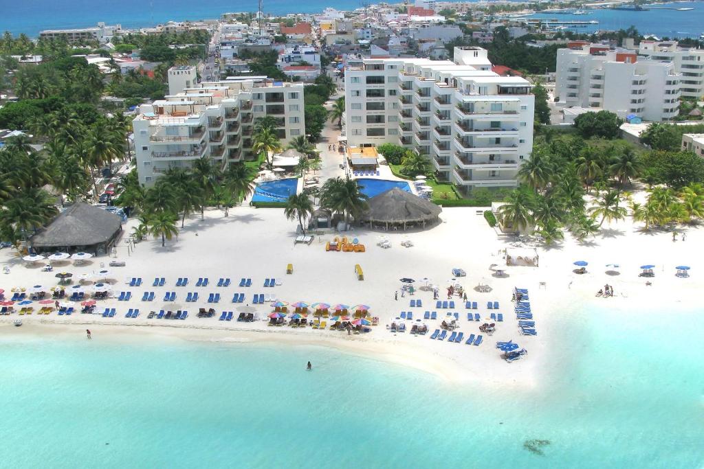 Edifício do Ixchel Beach Hotel em frente à praia, com espreguiçadeiras dispostas na areia branca