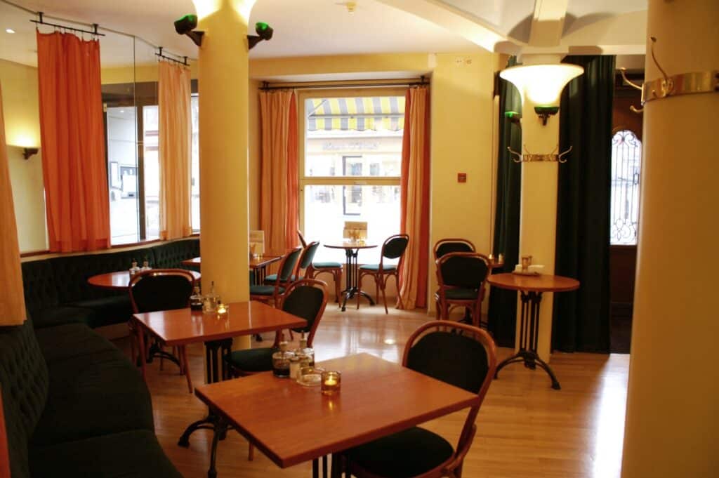 Restaurante do Altstadt Hotel Krone, com chão de madeira clara, colunas e cortinas cor de laranja.