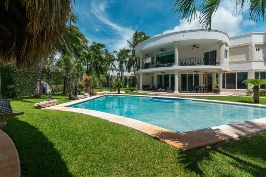 Piscina da Villa Palmeras com extenso relvado em redor e muitas árvores