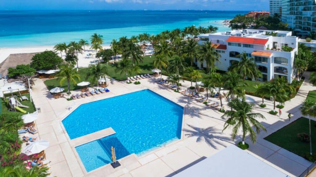 Piscina do Beachscape Kin Ha Villas & Suites junto à praia, rodeada de árvores e com um deck amplo