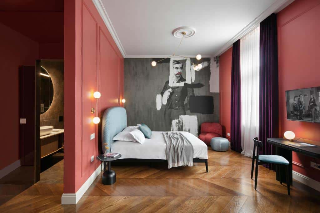 Quarto de hotel moderno com cama de casal, decoração em tons de vermelho e pintura artística na parede, no Almayer Art & Heritage Adults Only Hotel and Dépendance rooms (Cidade Velha)