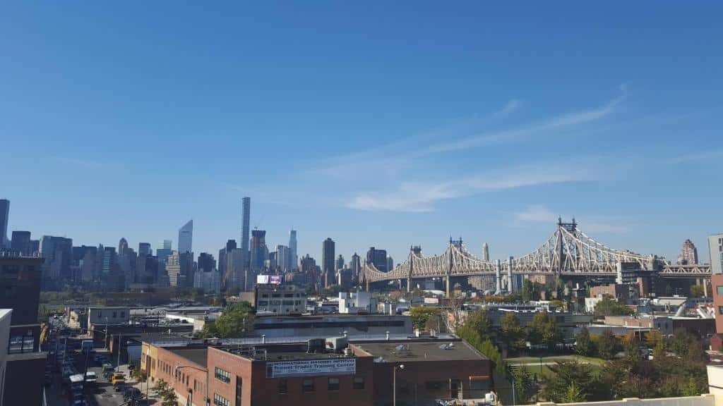 Horizonte de uma cidade com uma grande ponte suspensa e edifícios altos, sob um céu azul claro.